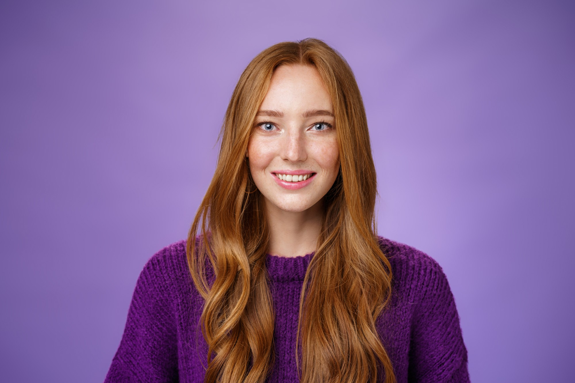 g redhead 20s girl with freckles long hair smiling joyfully with faith eyes prominent look posing against purple background